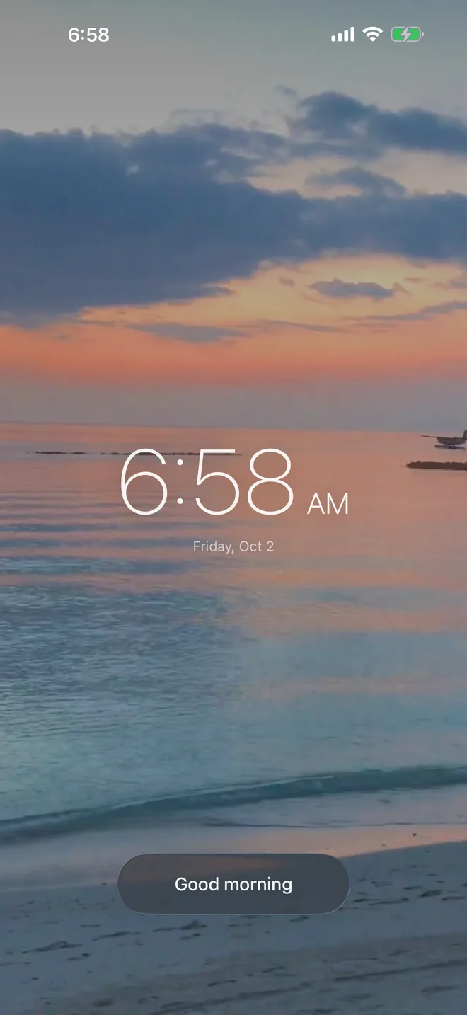 The morning screen: the same beach in the colours of dawn, the time 6:58 AM, and a Good morning button.